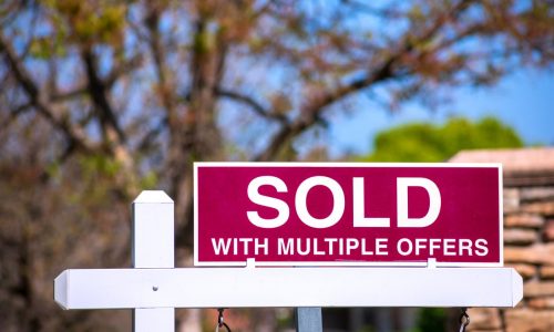 SOLD With Multiple Offers real estate sign near purchased house indicates hot seller's market in the desired neighborhood. Blurred outdoor background. Bidding war concept.